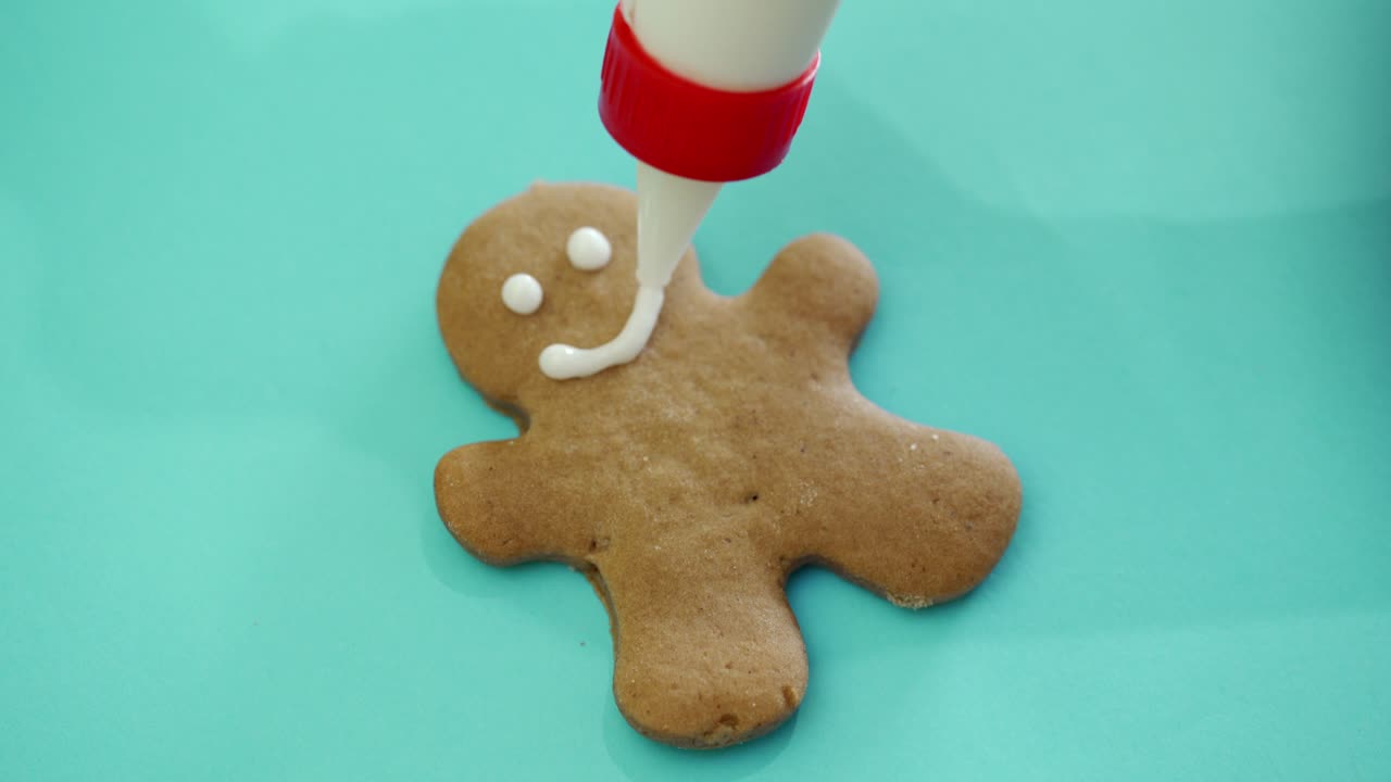 The process of making New Year's cookies in the form of a man on light background. Ginger man. Decorating products with using pastry bag. Close-up
