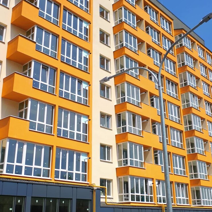 Nuevo edificio de apartamentos. Exterior de una casa de varios pisos de diseño moderno en la ciudad. Fachada de un edificio urbano luminoso con grandes ventanales.