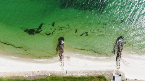 sun reflects on atlantic ocean water near sandy coastline, aerial top down ascend view