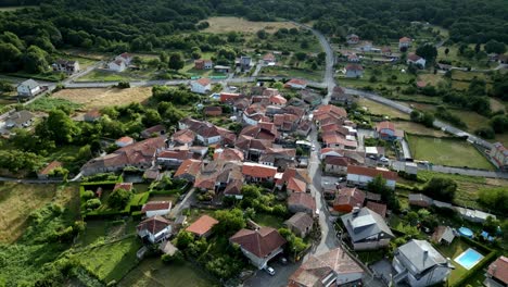 drone orbits around road running through city center of quaint cute houses in spanish countryside