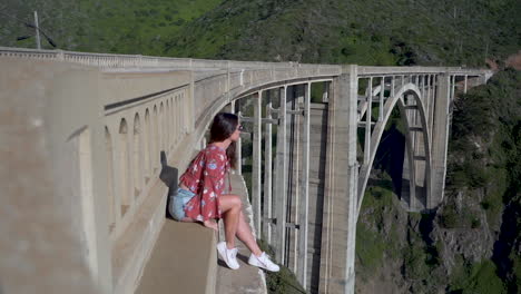 Girl-sitting-on-edge-of-bridge,-admiring-view-of-national-park-in-California