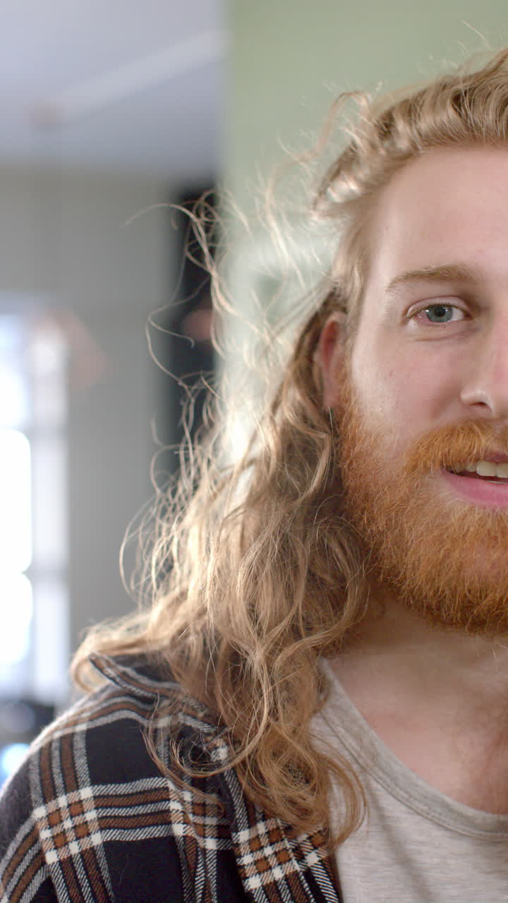 Vertical video of portait of caucasian man smiling at hair salon, in slow motion