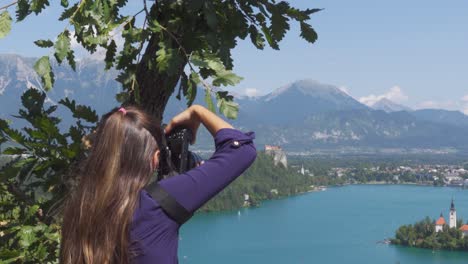 a woman taking photos with her camera of lake bled in slovenia