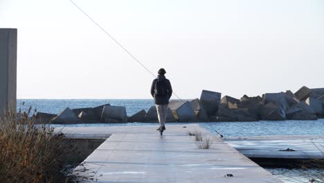 Young-Male-Riding-Electric-Scooter-on-Seafront-Jetty