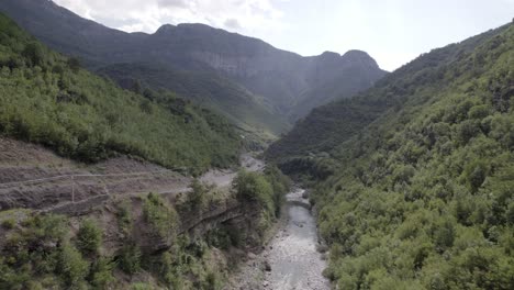 video de drones del plano frontal ascendente que avanza sobre el interior del río cemi en la carretera sh20 entre las montañas en albania entre tamarë y selcë, cielo nublado y aguas turquesas del río