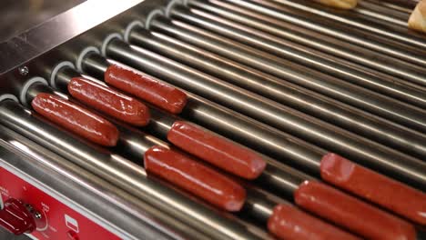 hot dogs cooking on a conveyor belt grill