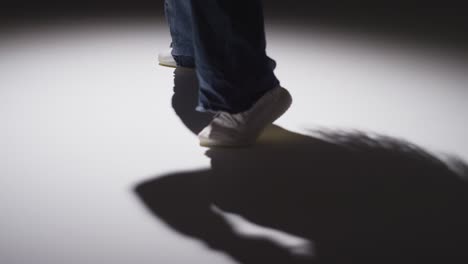 disparo de estudio de cerca que muestra los pies de una mujer bailando con iluminación baja contra un fondo gris 4