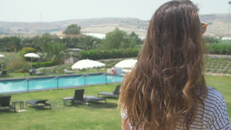 woman smiling and looking at the camera with a pool behind her