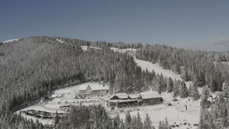 kope ski resort in the pohorje mountains with parking and visitors exploring, aerial pan right shot