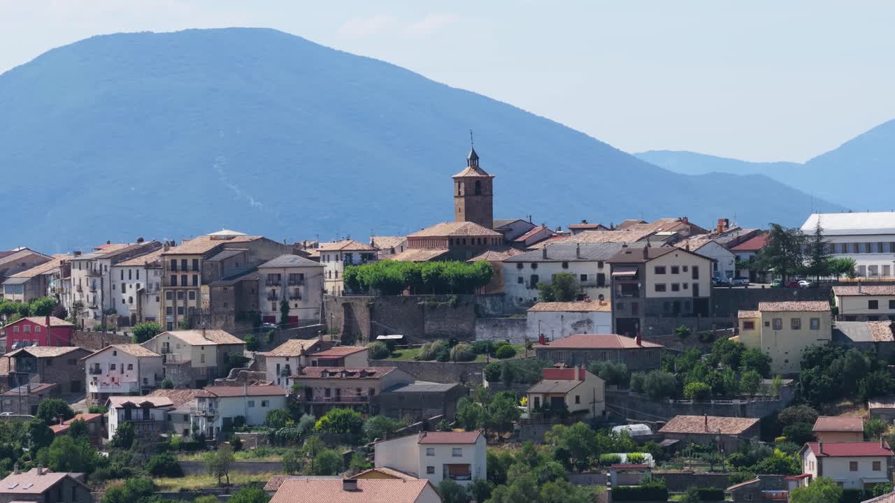 Veduta panoramica di un tradizionale paese europeo con una chiesa e montagne.