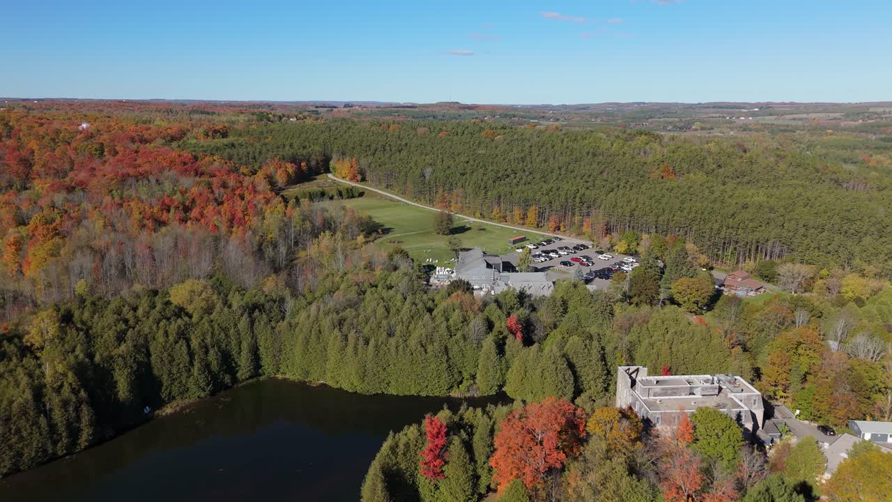 Aerial shot of autumn forests, a calm lake, and rolling hills in Alton, Caledon, Ontario, highlighting seasonal color, rural land, and natural terrain surrounding countryside estates