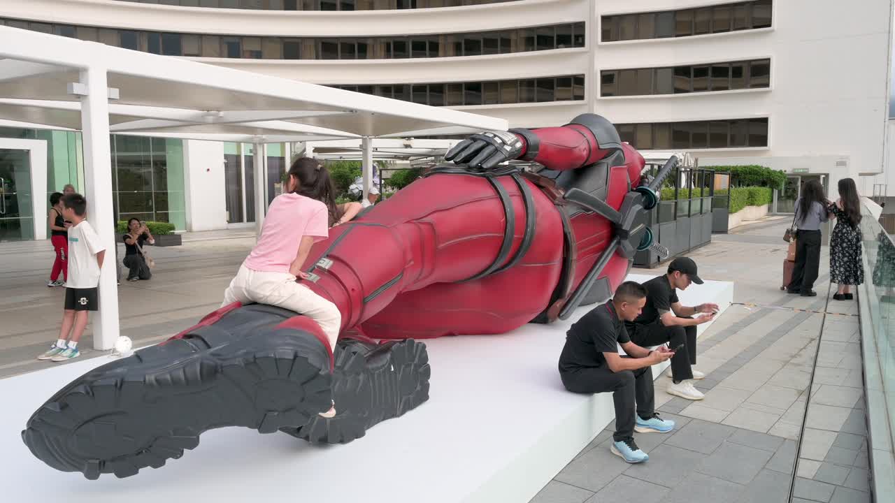 A child climbs the 8-meter Marvel Deadpool installation while locals and tourists snap photos. The display is part of the promotion for Disney's movie, "Deadpool and Wolverine," in Hong Kong.