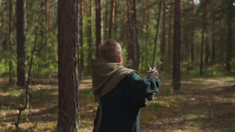 Kid-in-middle-age-costume-with-sword-runs-in-spring-wood