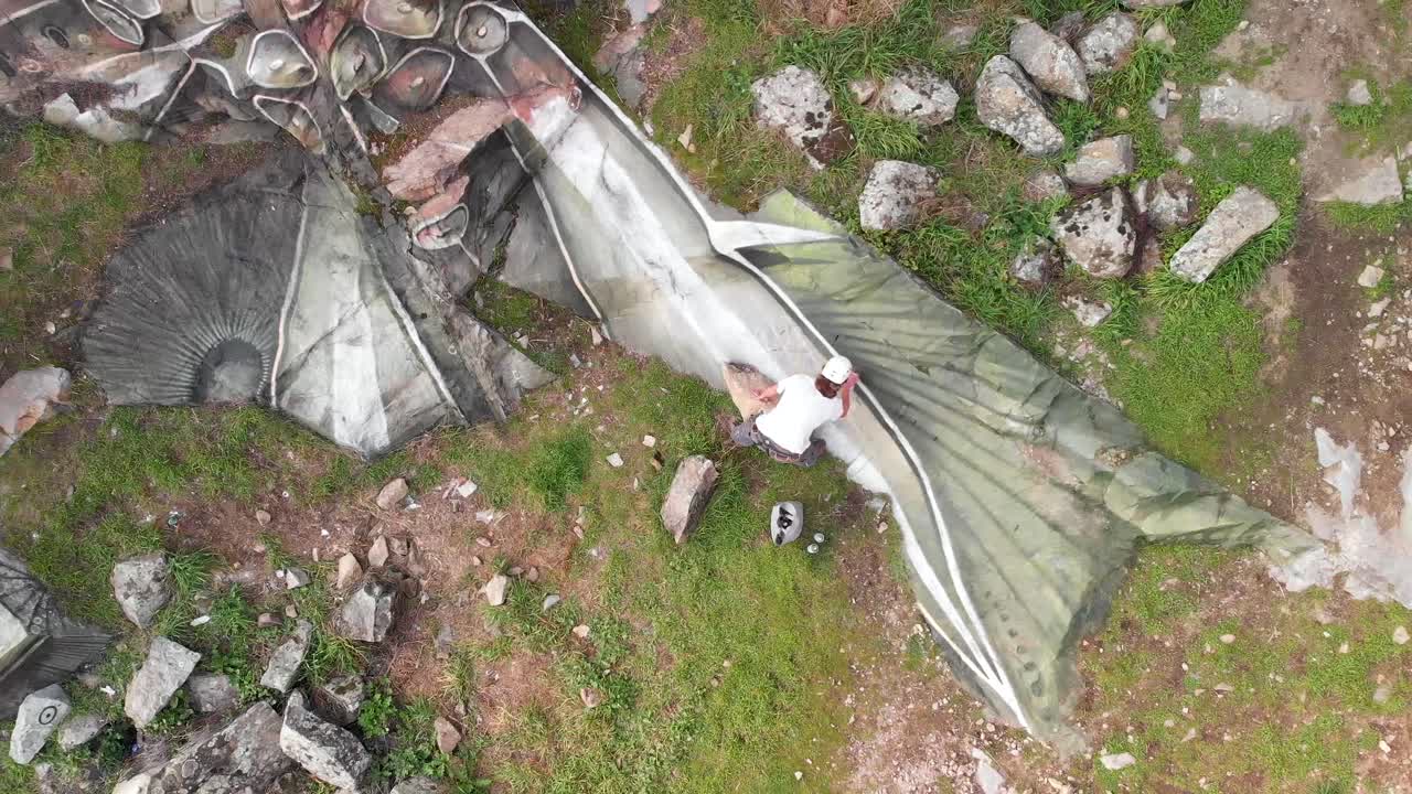 남성 화가 가 바위 절벽 에 그림 을 그리고 있다