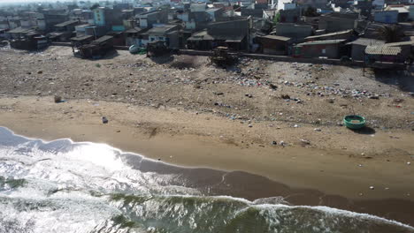 Aerial-dolly-left-flying-over-dirty-beach,-coast-of-Phan-Ri-Cua,-Vietnam