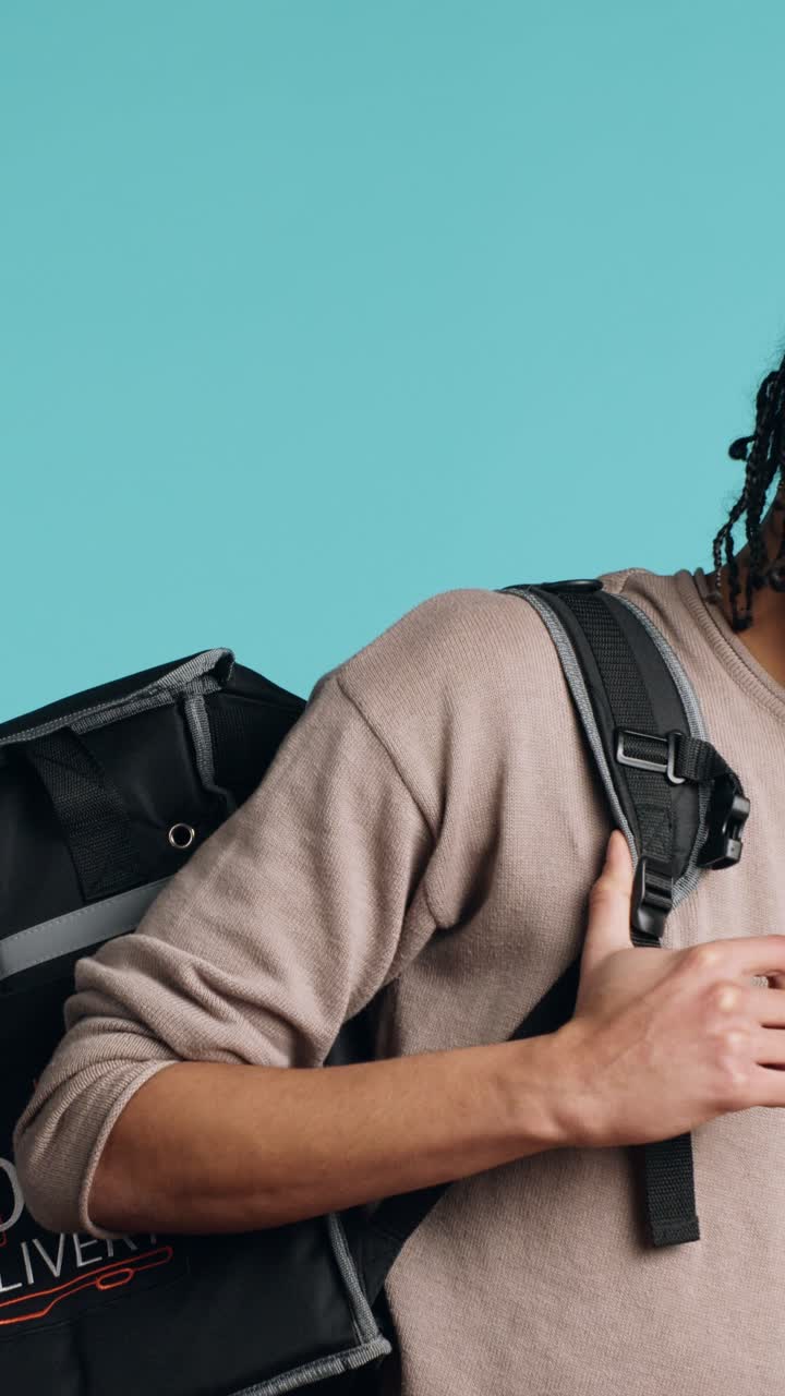 Vertical video Portrait of BIPOC courier delivering pizza order to client, camera background