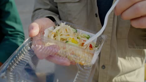 person eating a salad from a takeout container