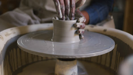 Close-up-view-of-female-potter-creating-pottery-on-potters-wheel-at-pottery-studio