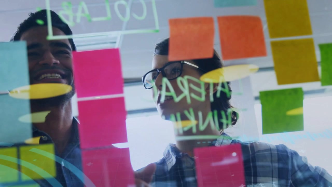 Pair reaching and pointing at glass, blue HUD aligning sticky notes and code, planning tech roadmap