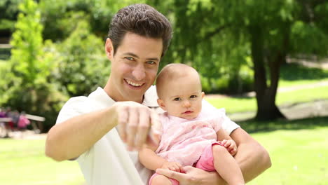 padre feliz sosteniendo a su niña en el parque