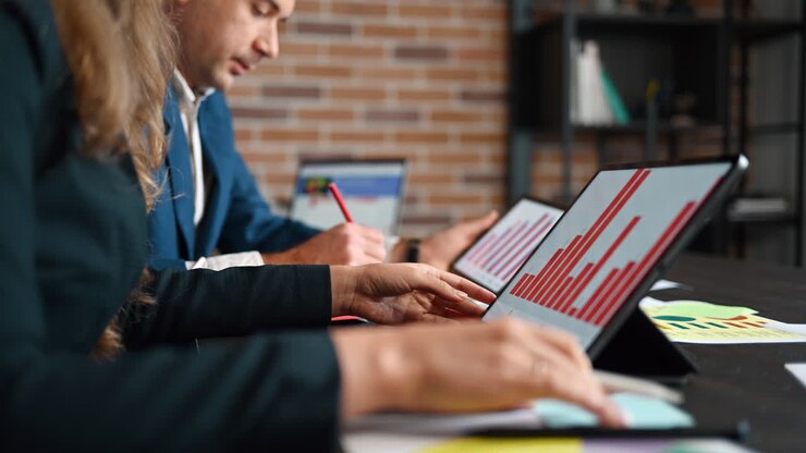 Two people working with charts at a table in an office