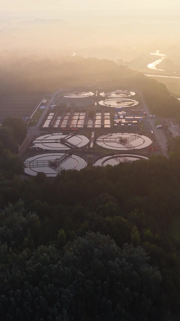 Vertical Video Retreating Aerial of Water Treatment Plant and wastewater recycling facility at sunrise. Clean tech, sustainability, and environmental engineering concept.