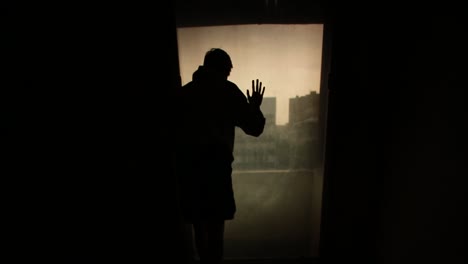 person looking out of window in the dark