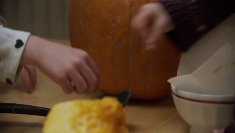 dos niños pequeños quitando las semillas de una calabaza para halloween