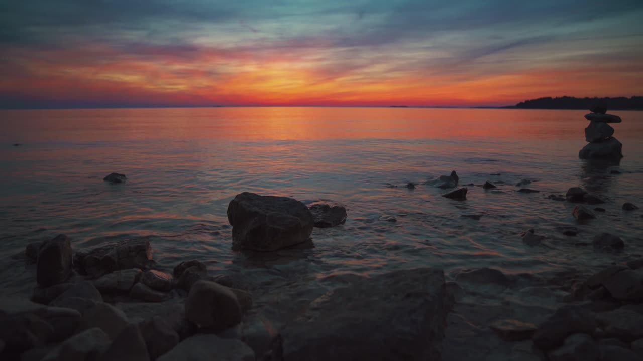 Cinemagraph / seamless video loop of a vibrant red sunset at a remote natural Tuscany seaside sand beach in Italy with dramatic sky and panoramic sea view. Blue and turquoise water at the scenic nature tourist vacation location.