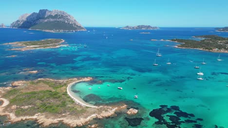 isla tavolara rodeada de barcos y mar azul turquesa en cerdeña, italia - antena 4k