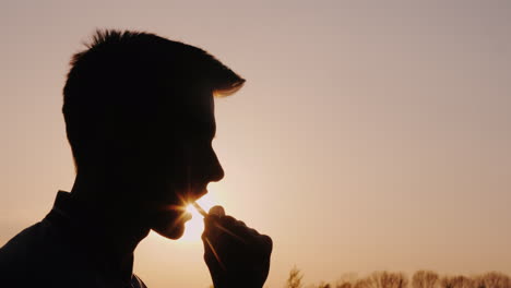 Profil-Eines-Teenagers,-Der-Snacks-Silhouette-Gegen-Die-Untergehende-Sonne-Isst