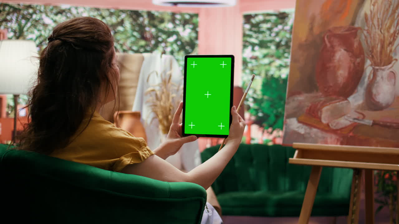 Woman using tablet with green screen while painting