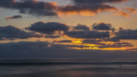 amazing beautiful golden sunset timelapse with light rays beaming through thick clouds over calm ocean waves flowing