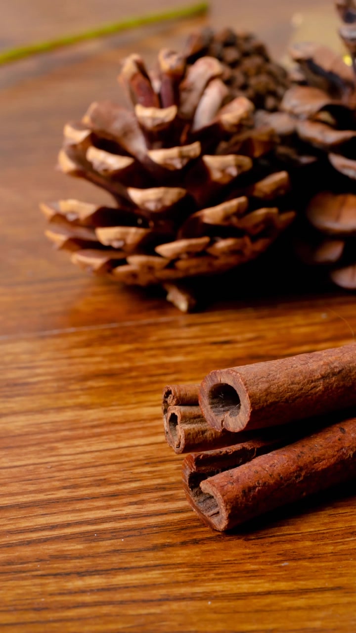 Animação de decorações de Natal, canela, pinhas e espaço para texto em fundo de madeira.