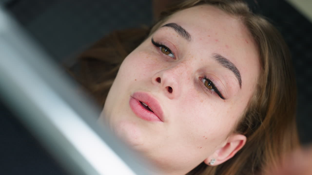 close up of focused young woman lying on gym bench breathing out after lifting barbell during workout session, showing effort and concentration with details of her expression and facial features