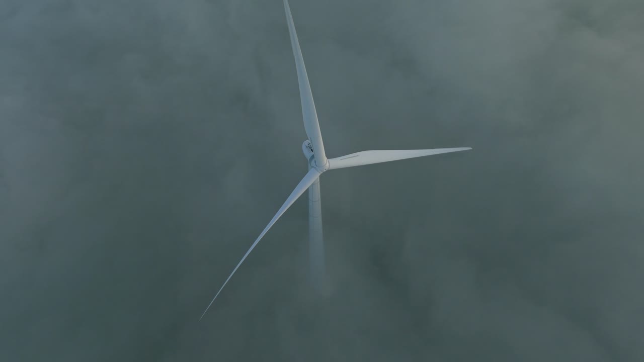 Wind turbines stand above low fog at sunrise on the Dutch coastline