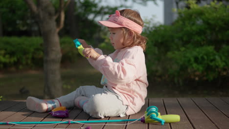 cute toddler sitting on deck playing with toy fishing set