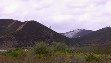 tres montañas en el metraje, una de las cuales está completamente despojada de todas las plantas y completamente ocupada por paneles solares: plano general
