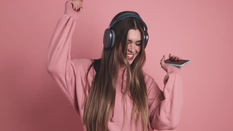 young woman dancing listening to music with mobile and headphones