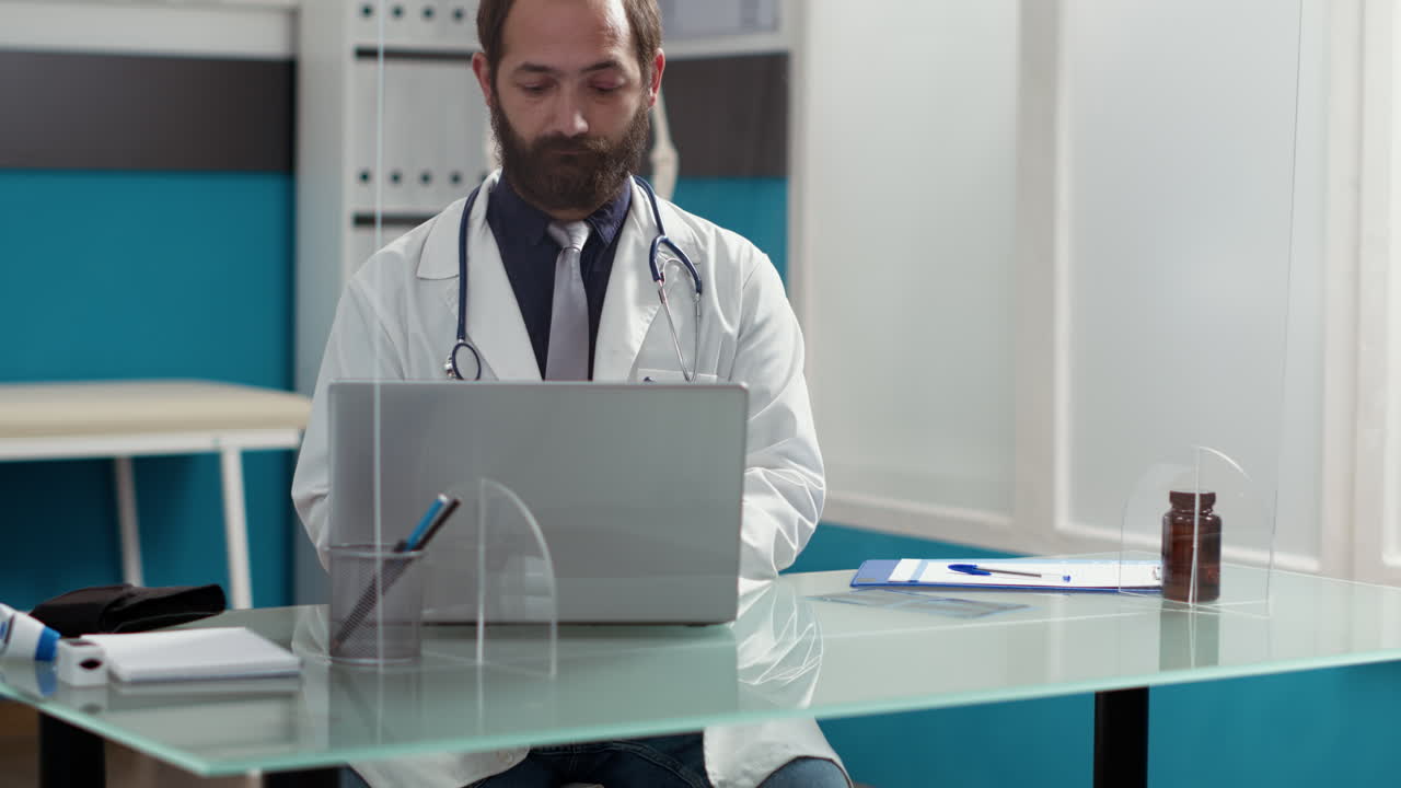 Portrait of general practitioner working on laptop at desk