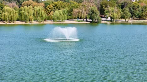 rotating closeup view of an artesian fountain in the middle of a small lake in tineretului park, bucharest, romania