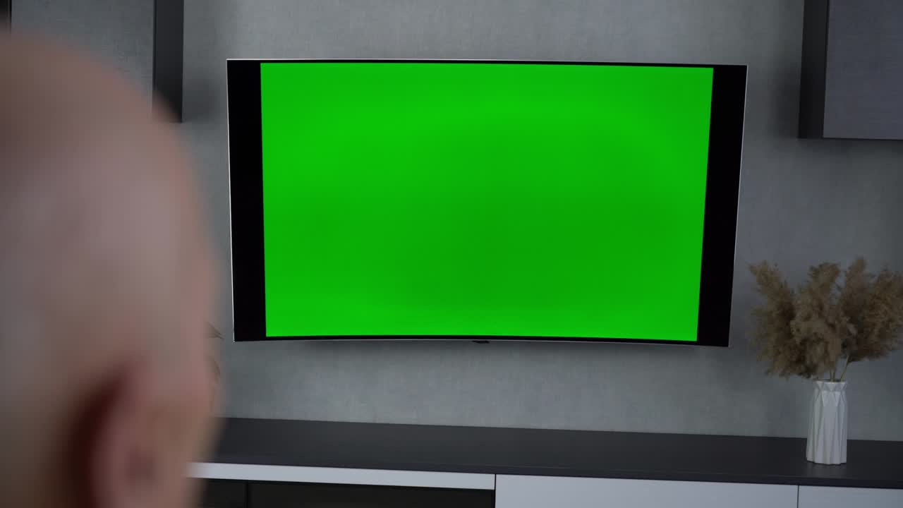 Grandfather sitting on coach at home and watching tv with blank screen