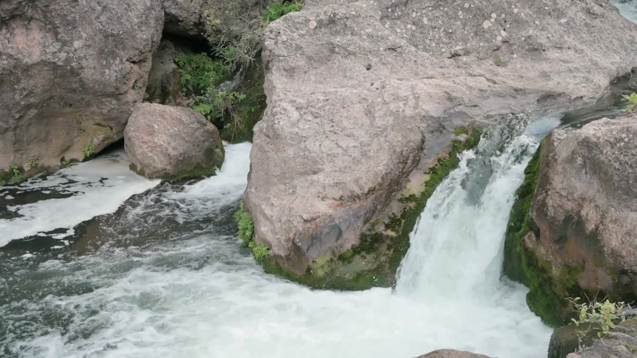 Small Mundo River waterfall in Albacete, framed by rocks and lush plant life