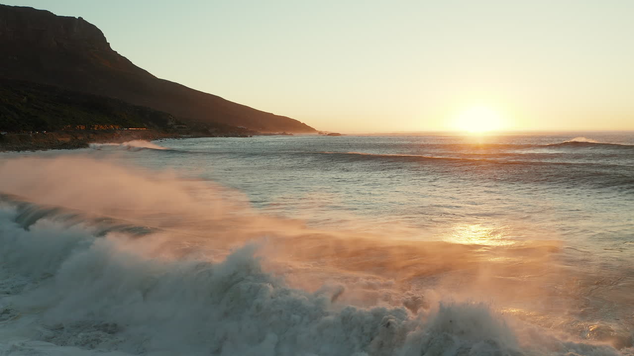 olas oceánicas con tono de puesta de sol en el horizonte en camps bay, ciudad del cabo, sudáfrica