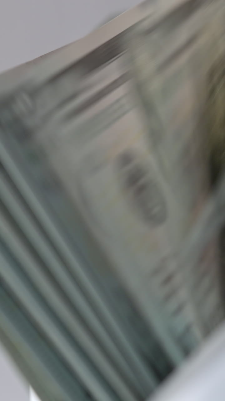 Hundred dollar bills falling on the holder in cash counting machine. Money counted machine stops working. Close up. Blurred backdrop. Vertical video