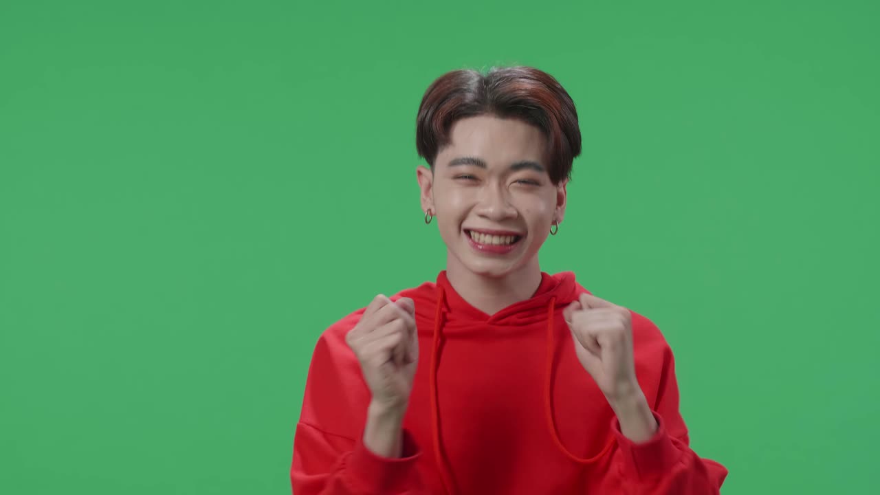 The Surprised Asian Transgender Male Positively Shaking His Head And Pressing Hishands To Her Face To The Camera In Green Screen Studio