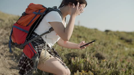 girl taking photo with her phone while backpacking on a sunny day