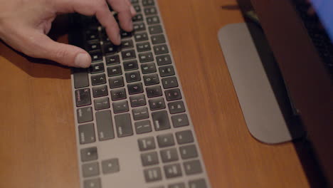 primer plano de un teclado de computadora de escritorio con la mano de un hombre escribiendo en él