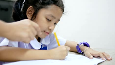 asian little girl in thai student uniform doing homework on wooden table select focus shallow depth of field