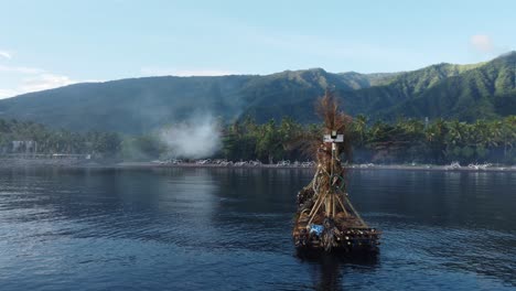 Floating-fishing-islands-in-the-sea-in-front-of-green,-misty-mountains-in-Bali-vertical-drone-rotation